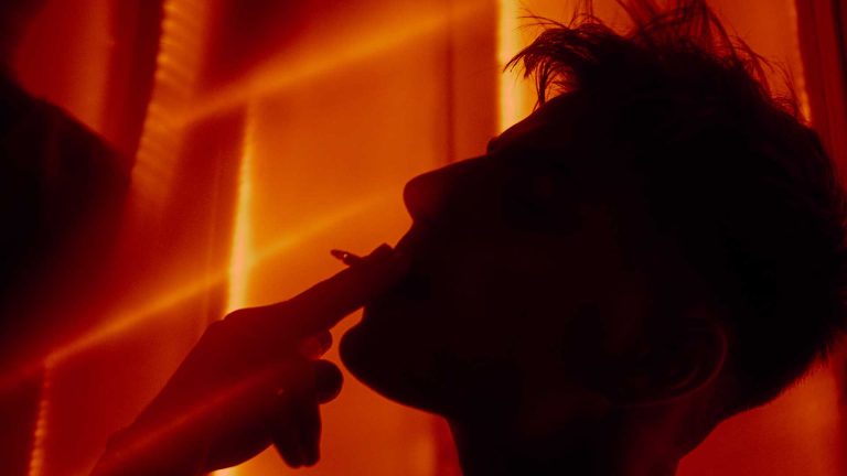 photo obscure d'un homme fumant une cigarette devant des lumières rouges par MITHRIL PRODUCTION production vidéos et photos